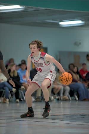 Teen boy in a scoliosis brace dribbling a basketball during practice