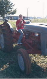 Starr riding a tractor in Oklahoma before her scoliosis diagnosis.