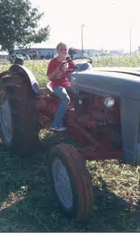 Starr riding a tractor in Oklahoma before her scoliosis diagnosis.